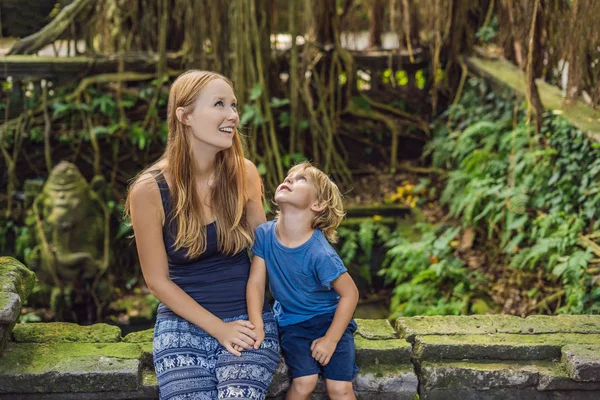 Mom and son travelers discovering Ubud forest in Monkey forest, Bali Indonesia. Traveling with children concept.