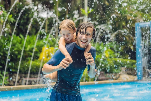 Dad and son have fun in pool during vacation at daytime