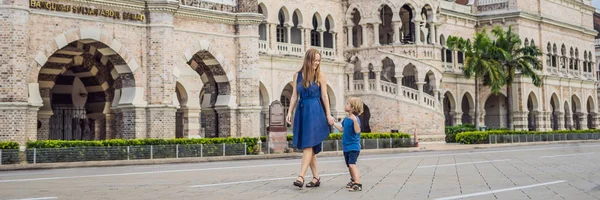 Mom and son on background of Sultan Abdul Samad Building in Kuala Lumpur, Malaysia. Traveling with children concept. BANNER, long format