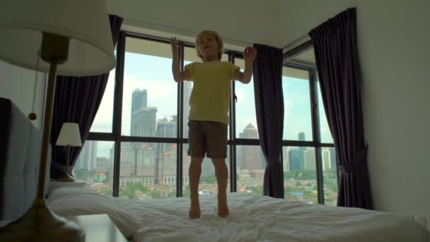 Медленный снимок маленького мальчика, прыгающего на кровати. Концепция матрасов и подушек — стоковое видео