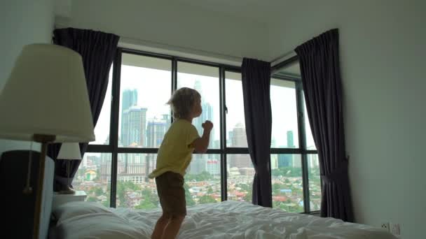 Fotografía en cámara lenta de un niño saltando sobre una cama. Concepto de colchón y almohada — Vídeos de Stock