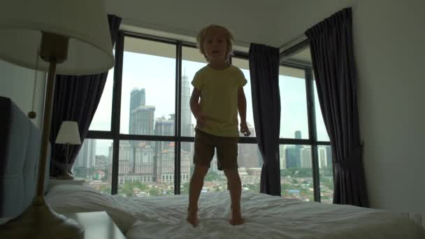 Filmagem em câmara lenta de um rapazinho a saltar numa cama. Conceito de colchão e almofada — Vídeo de Stock