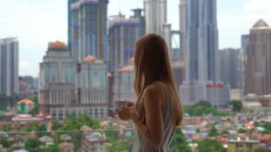Isıtmak içecekler sabah kahvesi tam bir şehir merkezi manzaralı onun dairenin balkonunda genç kadın.