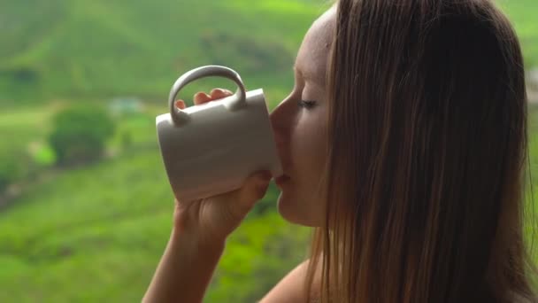 Jeune femme assise dans un café avec vue sur les plantations de thé des hautes terres et boire du thé . — Video