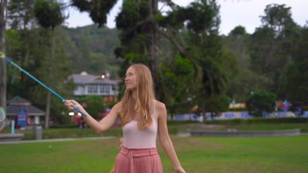 Повільний знімок молодої жінки, що робить великі мильні бульбашки в парку — стокове відео