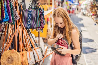 Genç kadın ünlü Bali rattan Bali, Endonezya yerel Hediyelik eşya pazarında eco torbaları seçme
