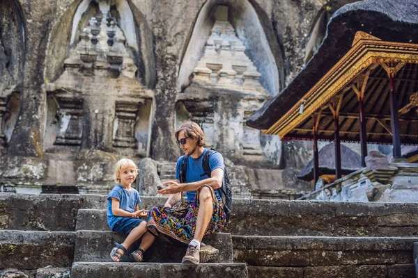 Pappa och son på bakgrund av Gunung Kawi. Forntida ristade i sten templet med kungliga gravar. Bali, Indonesien. Resor med barn koncept — Stockfoto