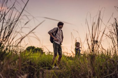 Baba ve oğul uzun otların arasında günbatımında iyi eğlenceler