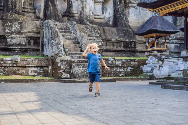A háttérben a Gunung Kawi fiú. Ősi faragott kő a templomban, a királyi sírok. Bali, Indonézia. Utazótáska-val a gyermek koncepció — Stock Fotó