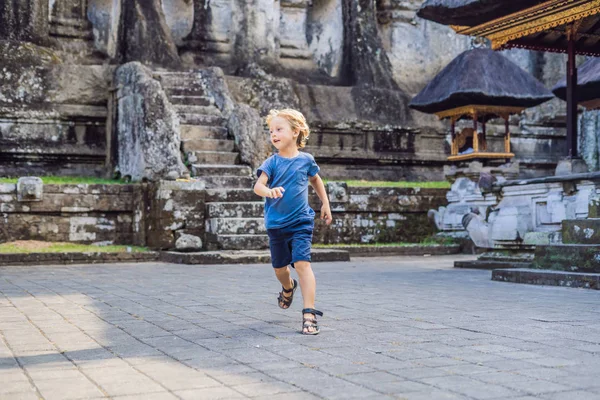 Un chico con antecedentes de Gunung Kawi. Antiguo tallado en el templo de piedra con tumbas reales. Bali, Indonesia. Viajar con concepto de niños — Foto de Stock