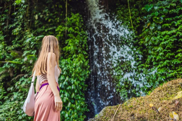 Widok z tyłu z młodą kobietę stojącą przed wodospad z jej ręce podniesione. Kobiece turystycznych z rękami wyciągniętymi patrząc na wodospad — Zdjęcie stockowe