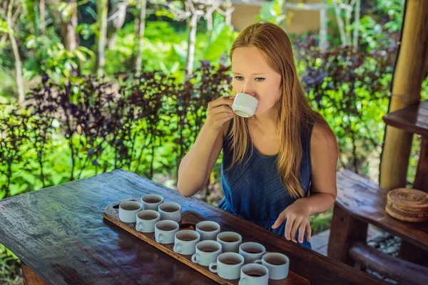 young woman tasting different kinds of traditional coffee and tea, Indonesia