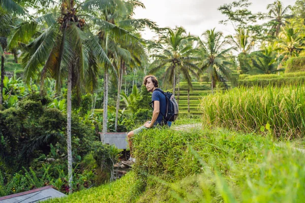 Male traveler sitting in green rice paddy in Ubud, Bali, Indonesia