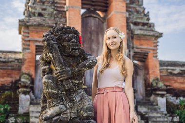 Genç kadın turist Tapınağı Taman Ayun, Bali, Endonezya, antik heykel yanında poz