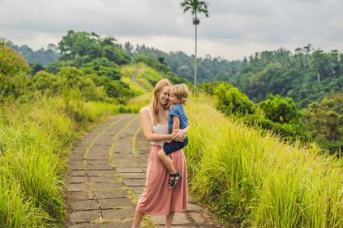 Anne holding oğul ve gülümseyen Campuhan Ridge yürümek, Bali