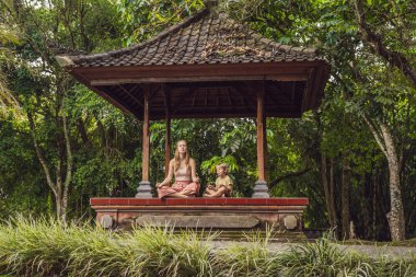 Anne ve oğlu meditasyon ve yoga geleneksel balinesse çardak içinde uygulamak 