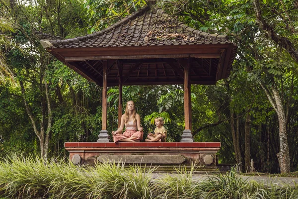 Anne ve oğlu meditasyon ve yoga geleneksel balinesse çardak içinde uygulamak 