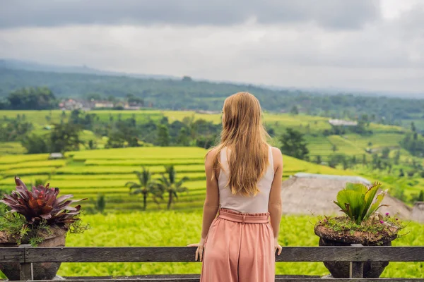 rear view of woman leaning on fence near Beautiful Jatiluwih Rice Terraces in Bali, Indonesia.