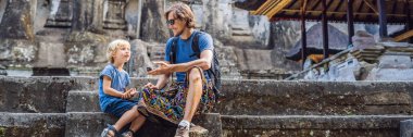 Baba ve oğul Gunung Kawi arka plan üzerinde. Antik tapınak kral mezarları ile taş oyma. Bali, Endonezya. Çocuk konseptiyle afiş, uzun biçimde seyahat