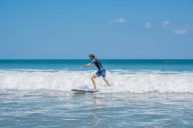 Genç adam okyanus dalgalarının Bali Adası, Endonezya sörf öğrenme