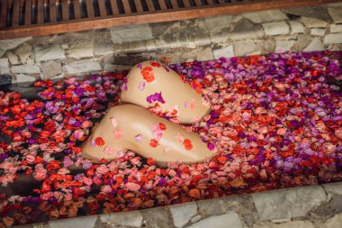 Diz yaprakları ve aroma yağı ile spa banyo içinde kadın.