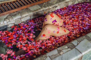 Diz yaprakları ve aroma yağı ile spa banyo içinde kadın.