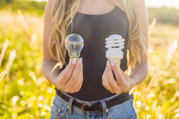 woman holding incandescent lamp and energy-saving lamp in hands