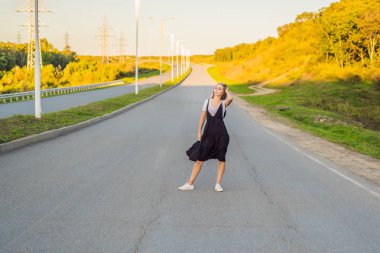 Güzel genç kadın yolda kırsal pitoresk peyzaj üzerinde poz.