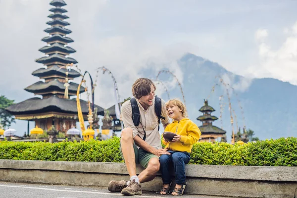 お父さんと息子のプラ ウルン ブラタン バリ島 インドネシアのヒンズー教の寺院の近くに座って — ストック写真