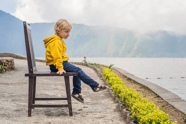 Мальчик Сидит Стуле Озера Братан Горами Покрытыми Облаками — стоковое фото