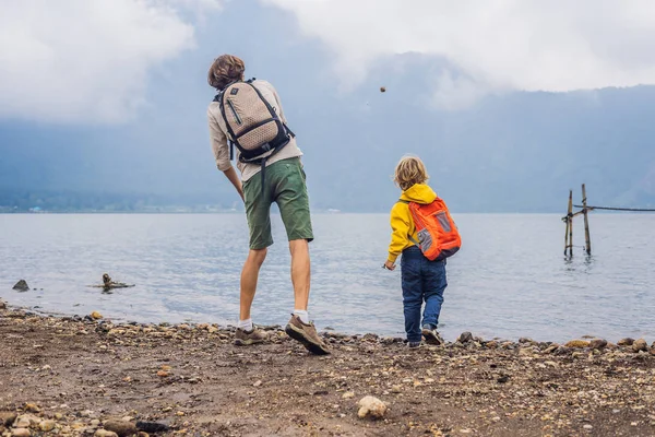 Father and son throwing stones at lake Bratan