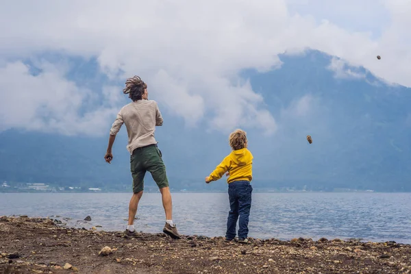 Father and son throwing stones at lake Bratan