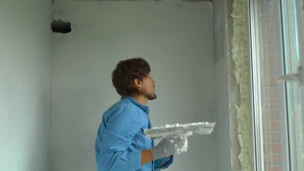 Повільний знімок молодого художника, що наносить шпаклівку на стіни — стокове відео