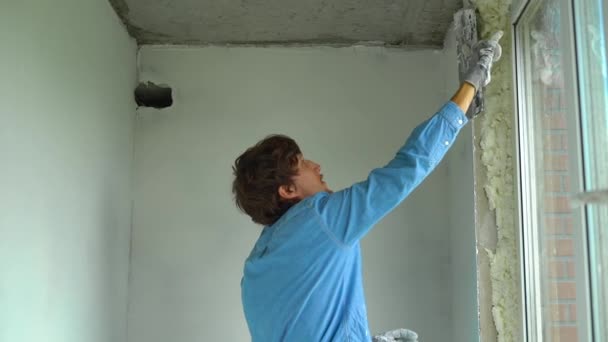 Slowmotion Shot Of A Young Painter Applying Putty On The Walls