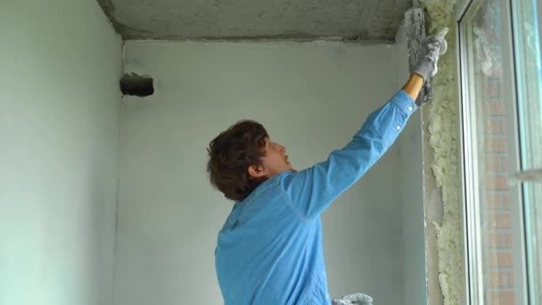 Fotografía en cámara lenta de un joven pintor aplicando masilla en las paredes — Vídeo de stock