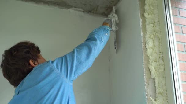 Plan au ralenti d'un jeune peintre appliquant du mastic sur les murs — Video