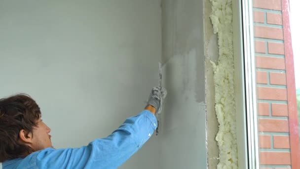 Медленный снимок молодого художника, накладывающего шпаклевку на стены — стоковое видео
