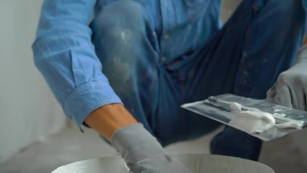 Slowmotion strzał młodego malarza, stosując putty na ścianach — Wideo stockowe