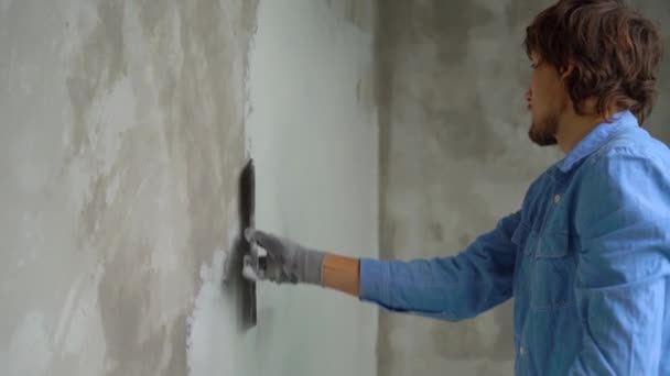 Slowmotion skott av en ung målare tillämpa kitt på väggarna — Stockvideo