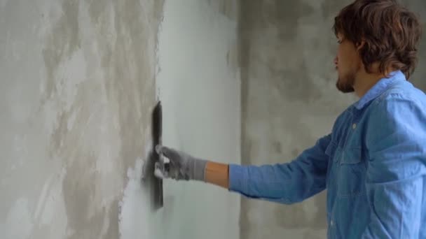 Plan au ralenti d'un jeune peintre appliquant du mastic sur les murs — Video