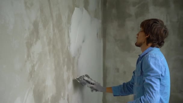 Zeitlupenaufnahme eines jungen Malers, der Kitt auf die Wände aufträgt — Stockvideo