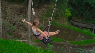 Tropikal bir uçuruma büyük salıncakta sallanan bir genç kadın görüntüsünü Slowmotion