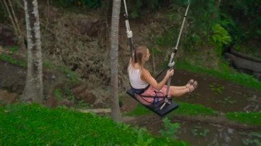 Tropikal bir uçuruma büyük salıncakta sallanan bir genç kadın görüntüsünü Slowmotion
