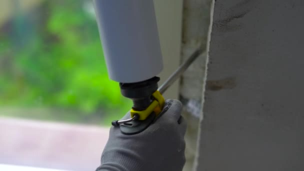 Slowmotion shot of a young man installing plastic window. Installer fills the seams with foam — Stock Video