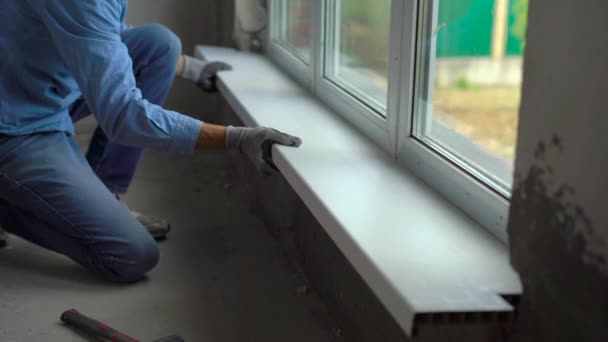 Young man installing windowsills of a plastic window — Stock Video