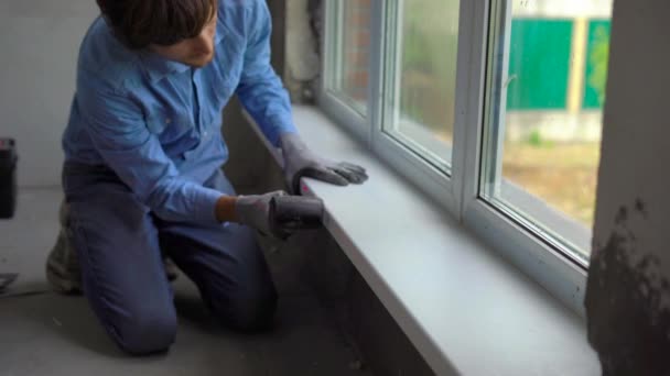 Jeune homme installant des appuis de fenêtre d'une fenêtre en plastique — Video