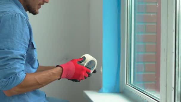 Un joven instalando una ventana de plástico. Instalador llena la pendiente de la ventana de plástico con una espuma de montaje — Vídeo de stock