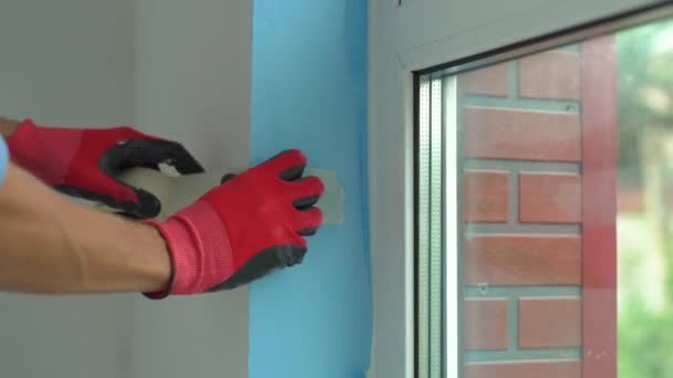 Ein junger Mann beim Einbau eines Kunststofffensters. Installateur füllt Schräge des Kunststofffensters mit Montageschaum — Stockvideo