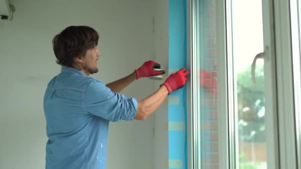 Ένας νεαρός άνδρας που την εγκατάσταση πλαστικό παράθυρο. Εγκαταστάτη γεμίζει την κλίση του πλαστικό παράθυρο με ένα αφρώδες υλικό στερέωσης — Αρχείο Βίντεο