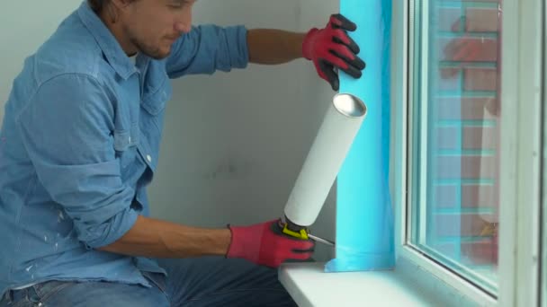 Een jonge man, installeren van kunststof venster. Installateur vult de helling van kunststof venster met een montage-schuim — Stockvideo